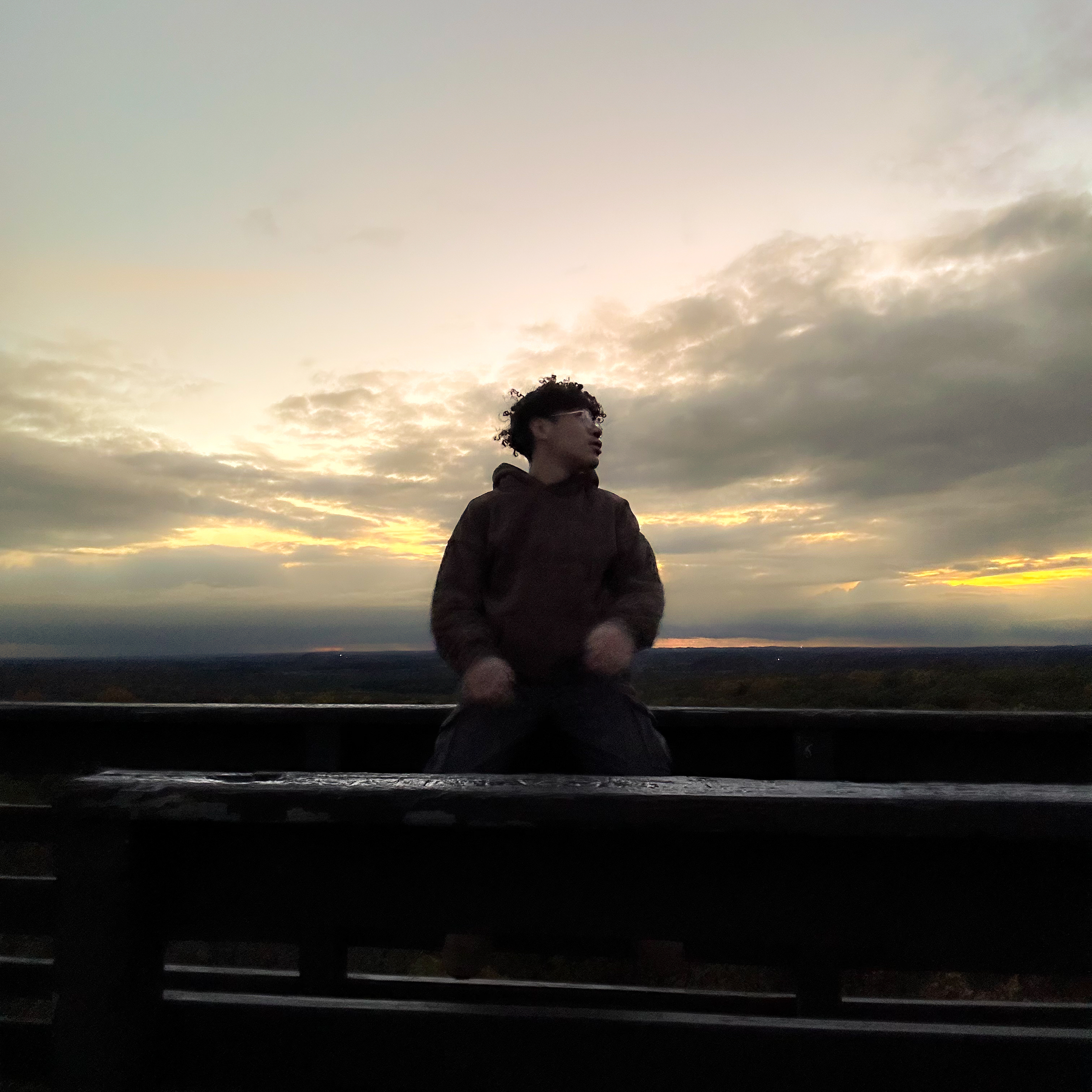 Person sitting on a lookout tower at sunset